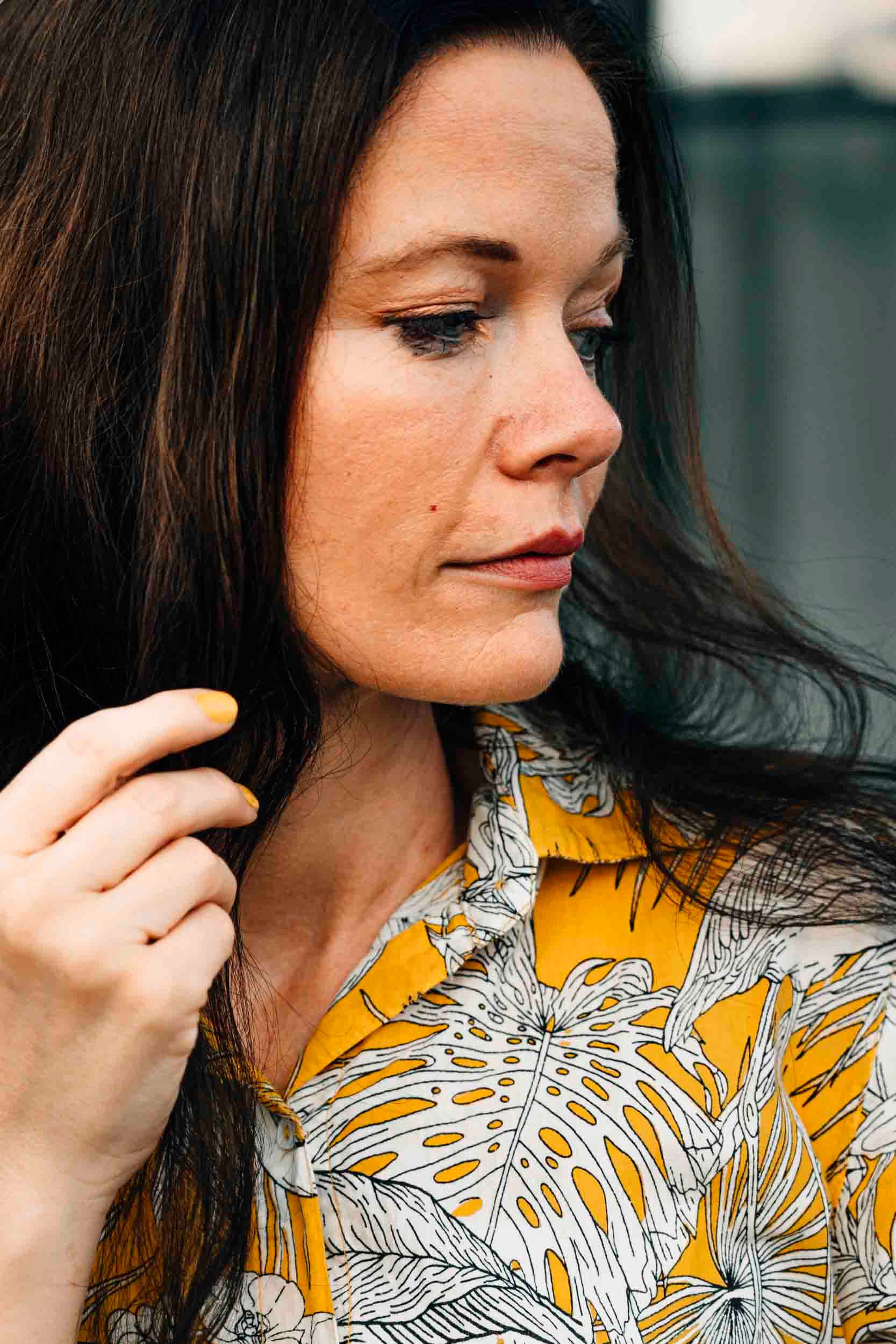 Close-up portrait of a woman in a floral yellow shirt, showcasing elegance.