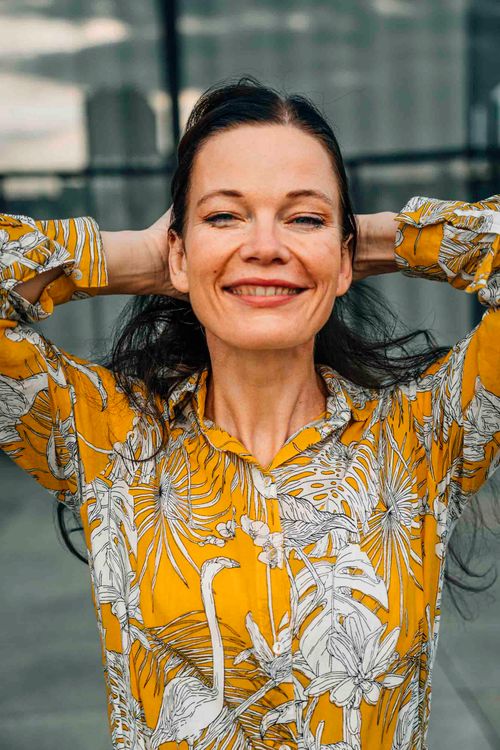 Free A joyful woman in a vibrant yellow shirt poses confidently outdoors in Berlin. Stock Photo