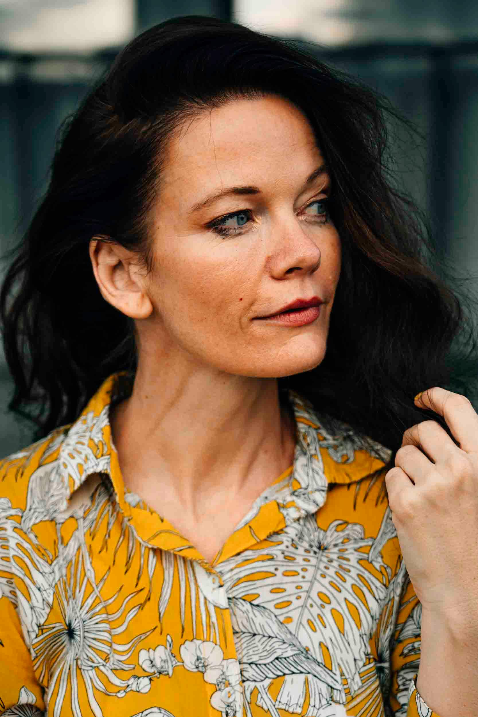 Stylish woman in yellow floral shirt with a serene expression, perfect for lifestyle or fashion use.