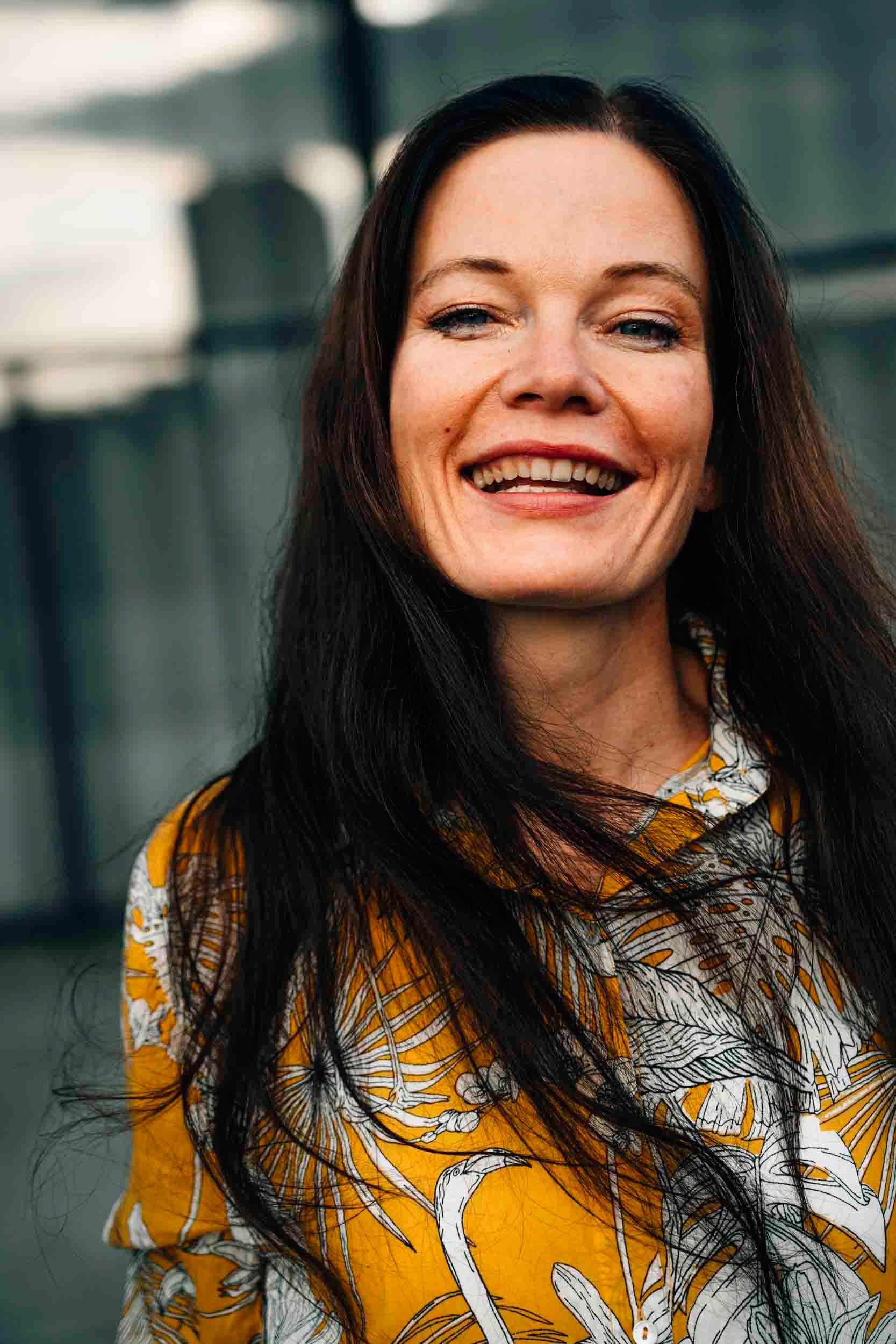 Portrait of a smiling woman in a stylish yellow blouse outdoors in Berlin.