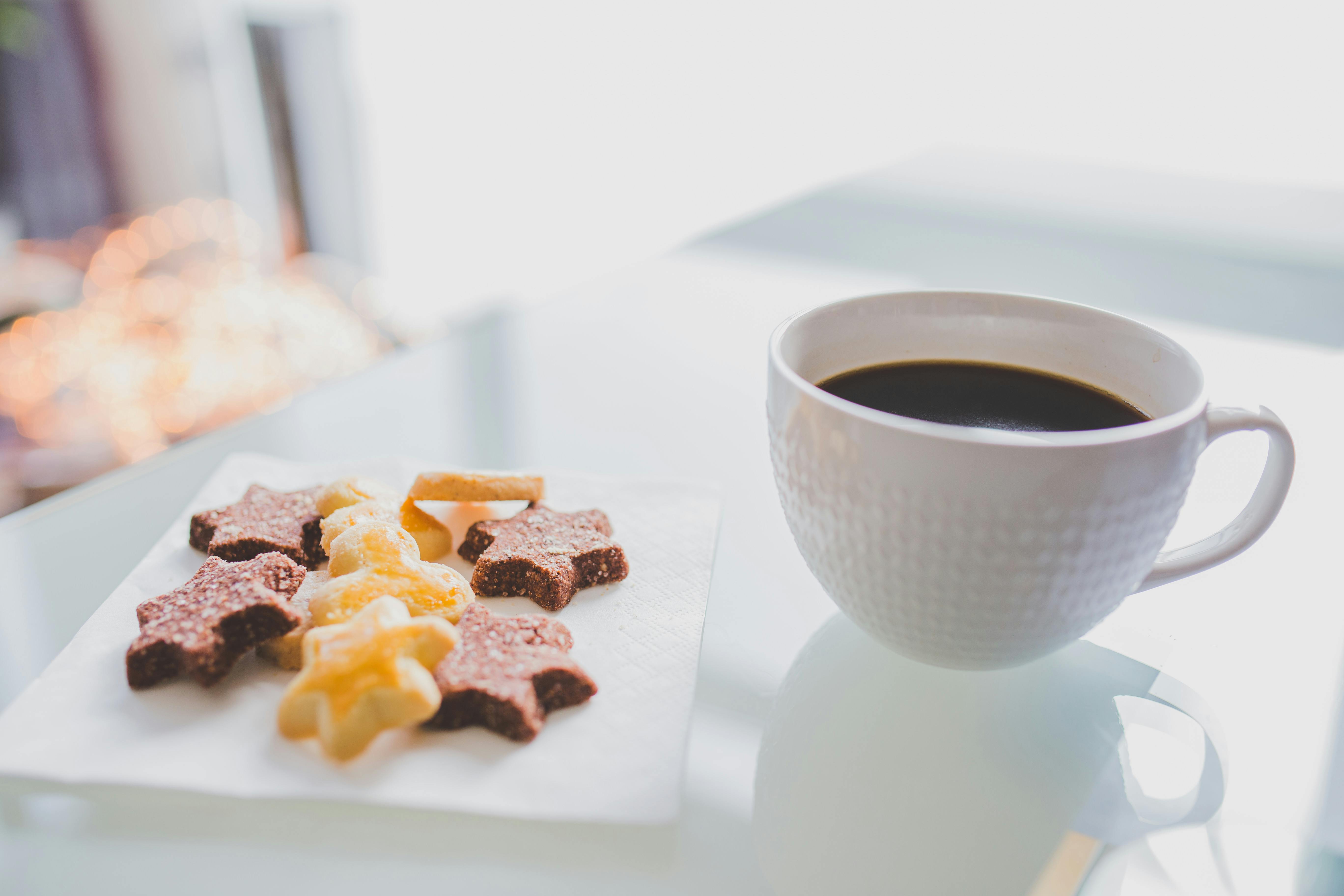 White Tea Cup Beside White Square Saucer With Star Shaped Cookies