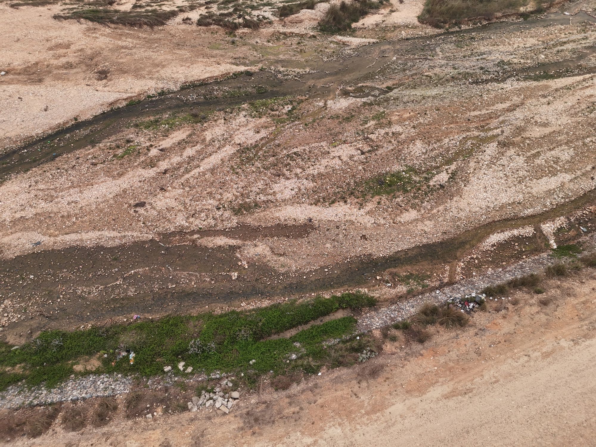 Lecho de un río parcialmente seco con rocas y bancos de arena al descubierto