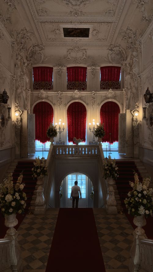 Free A person stands in a lavishly decorated historic mansion with ornate architectural details. Stock Photo