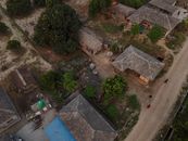 Aerial shot of a traditional village with wooden houses and dirt roads in Nepal, showcasing rural life.