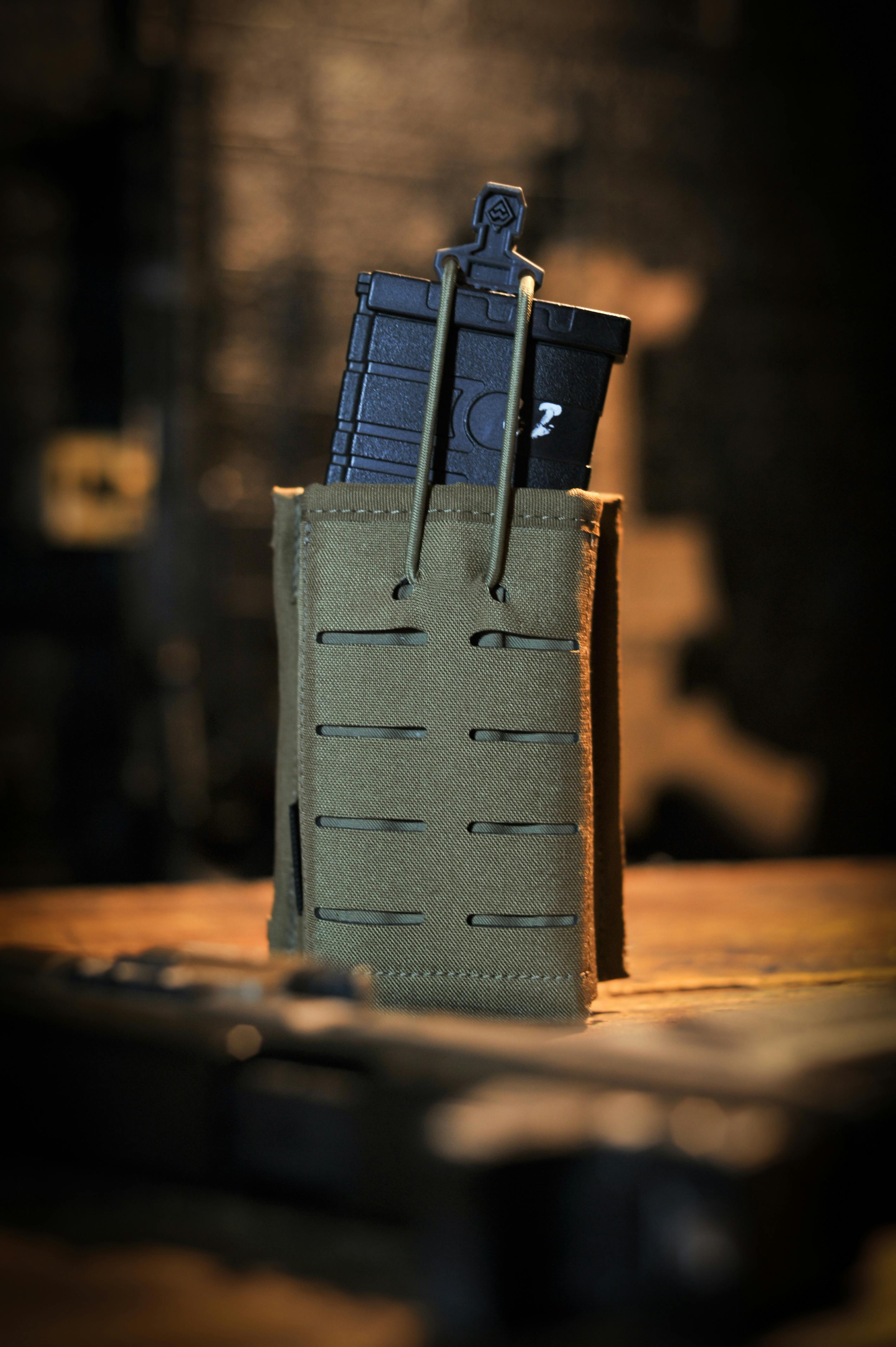 Gratis Primo piano di una custodia tattica per caricatori contenente munizioni, su uno sfondo sfocato. Foto a disposizione