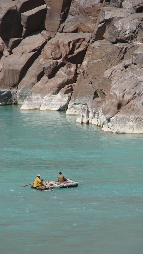 Free Two rafters paddle through the stunning turquoise river flanked by rocky cliffs in Gilgit-Baltistan. Stock Photo