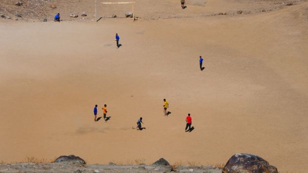A group of children playing soccer on a sandy field in Gilgit-Baltistan.