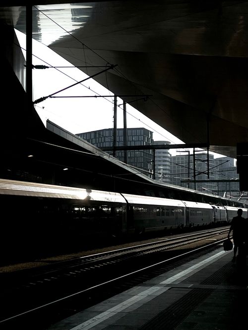 Free Silhouetted train and passenger at an urban station during sunset. Stock Photo
