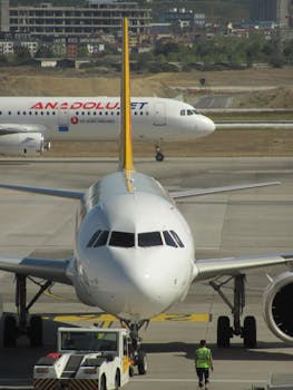 Front view of aircraft on runway with another plane in background at a busy airport.