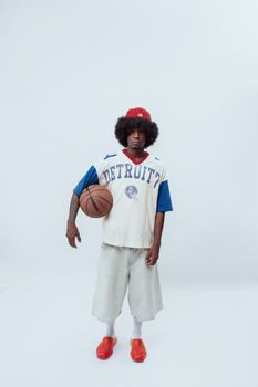 Man in vintage basketball attire posing with ball against a white backdrop.
