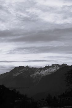 Striking black and white photograph of the Italian Alps in Chiavenna, showcasing dramatic clouds and snow-capped peaks. 33975787