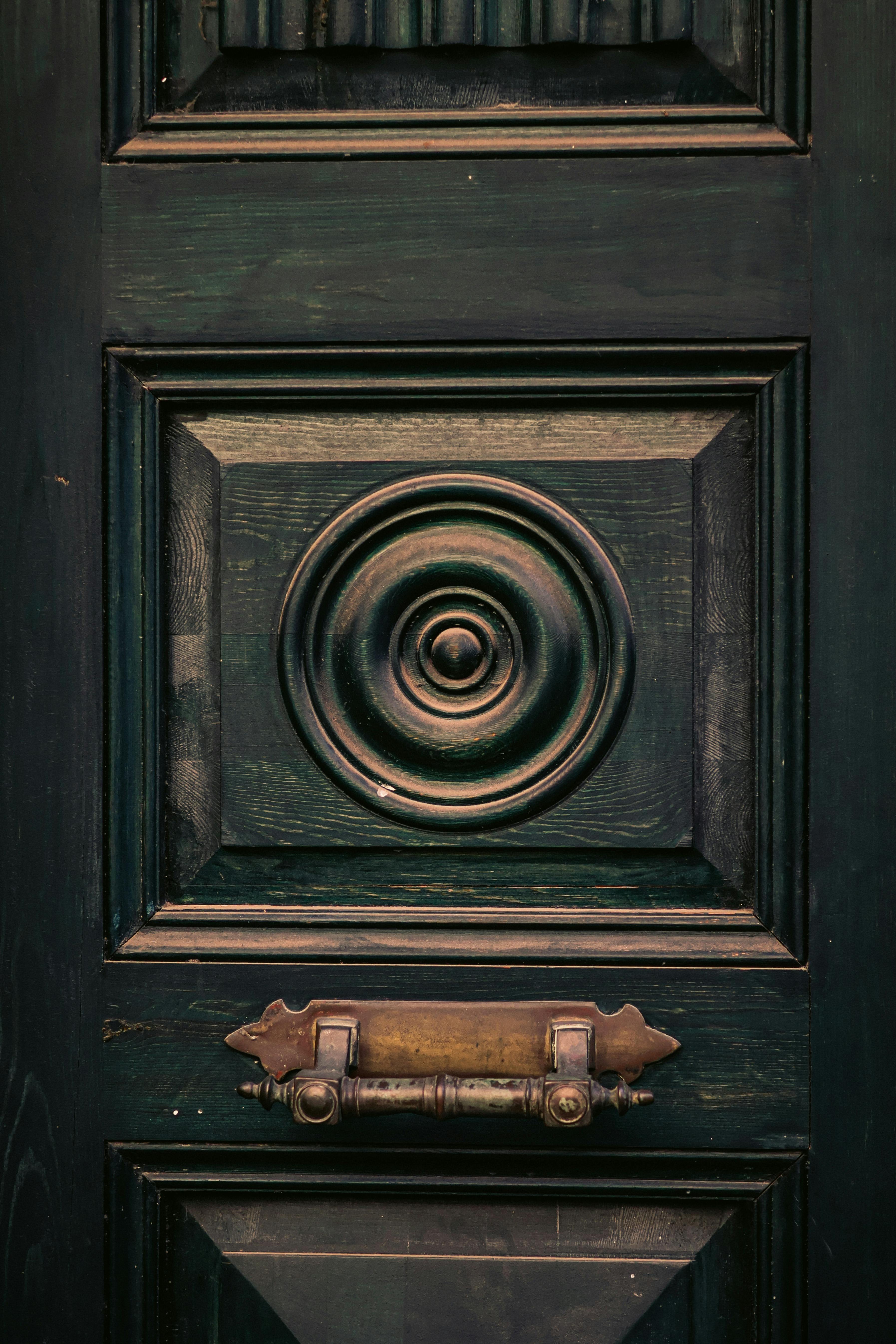 Kostnadsfria Närbild av en elegant vintage trädörr med en utsmyckad mässingsknacker och invecklad paneldesign. Stock foto