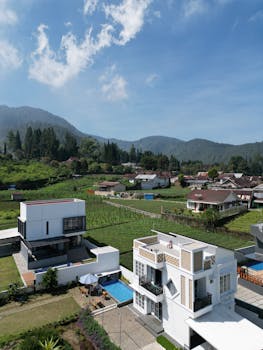 Modern villa with pool surrounded by lush green valley and mountains.