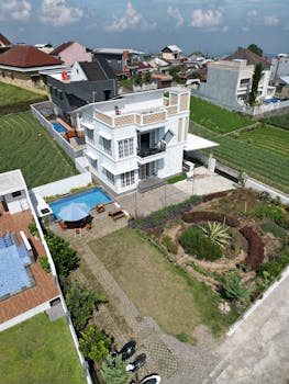 Aerial view of a modern villa with a garden and pool in a suburban area.