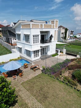 Aerial view of a modern suburban house with a private pool and lush garden.