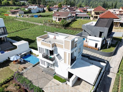 Aerial view of a modern house with a pool, located in a scenic hillside neighborhood.