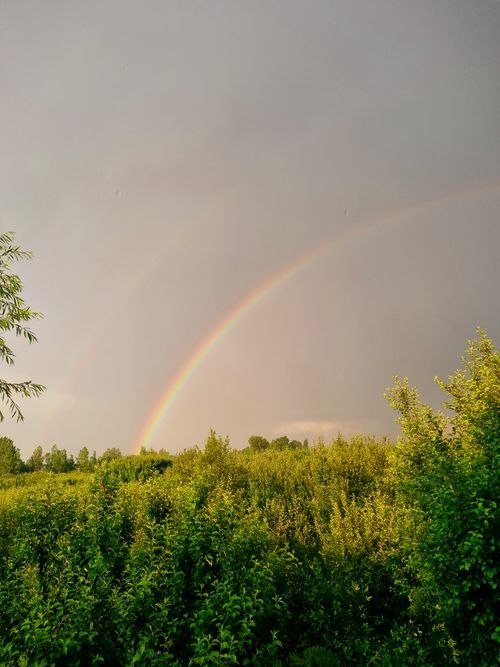 Free A stunning double rainbow arcs over a lush green landscape, symbolizing hope and renewal. Stock Photo