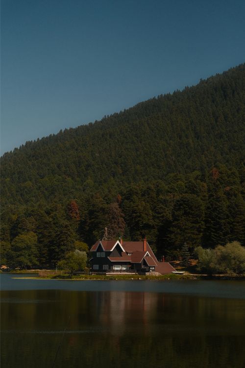 Free Serene view of a house by a forested lake in Bolu, Türkiye, reflecting natural beauty. Stock Photo