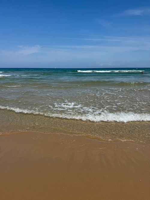 Free Tranquil beach scene at Oliva, Spain, with gentle waves and clear skies. Stock Photo