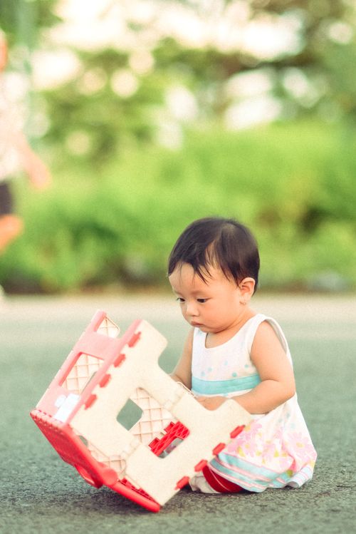 Free Cute baby playing with a toy house outdoors, enjoying a sunny day. Stock Photo