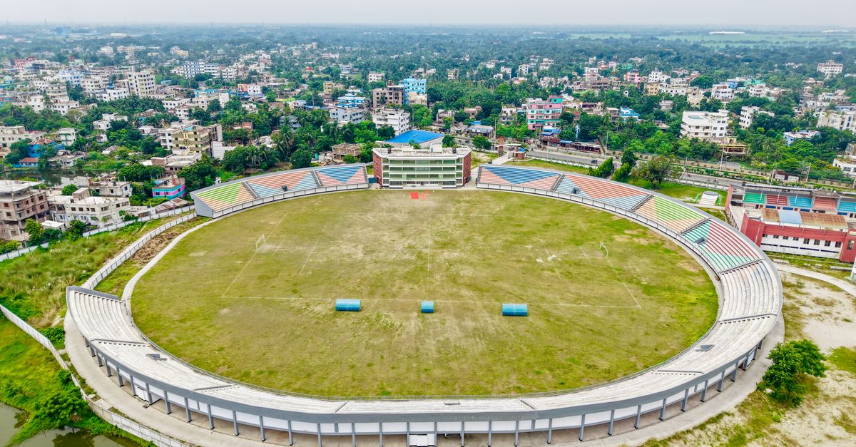 Aerial view of an empty football stadium surrounded by a bustling cityscape.