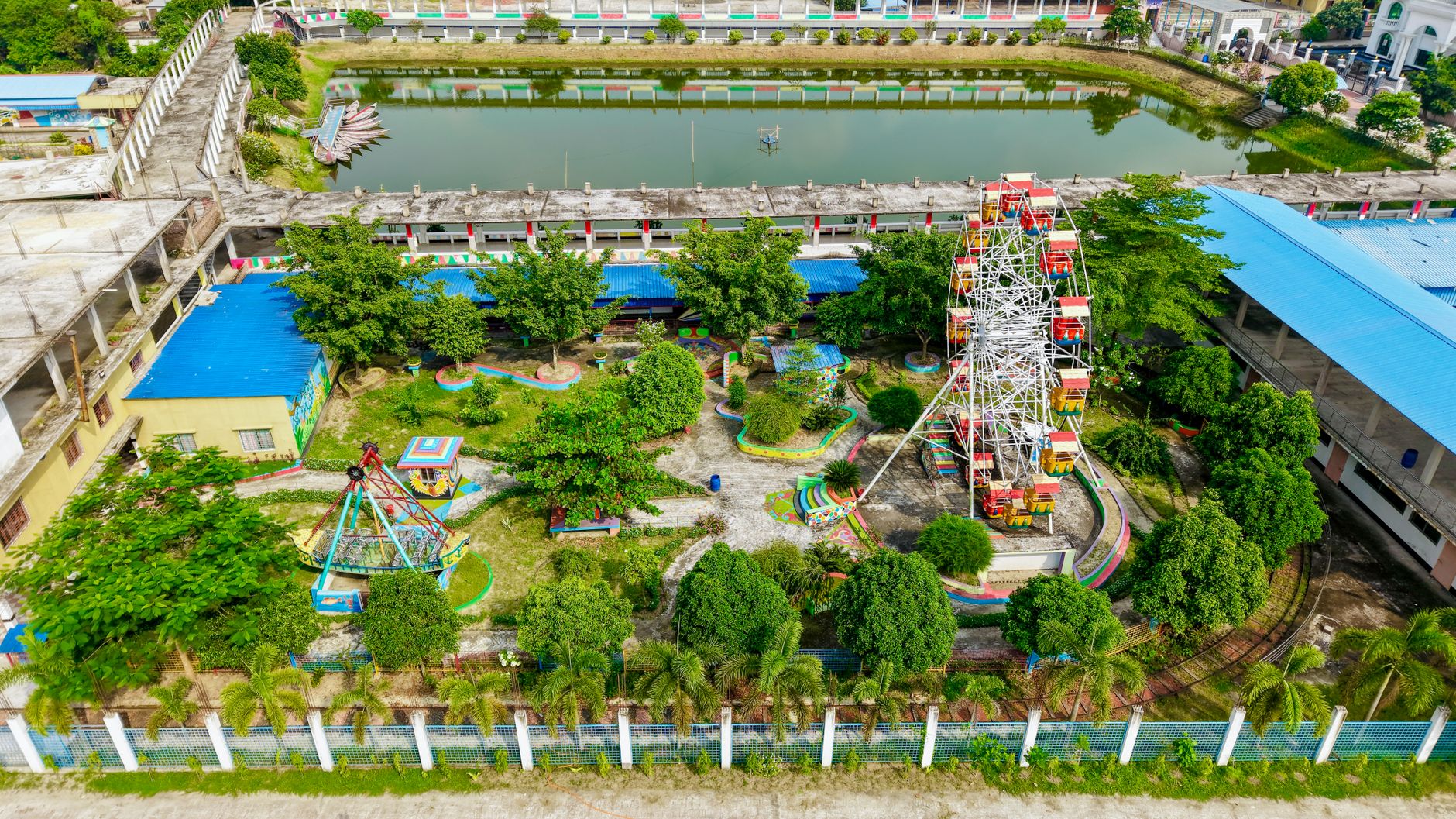 A colorful aerial view of a small amusement park featuring a Ferris wheel and greenery.