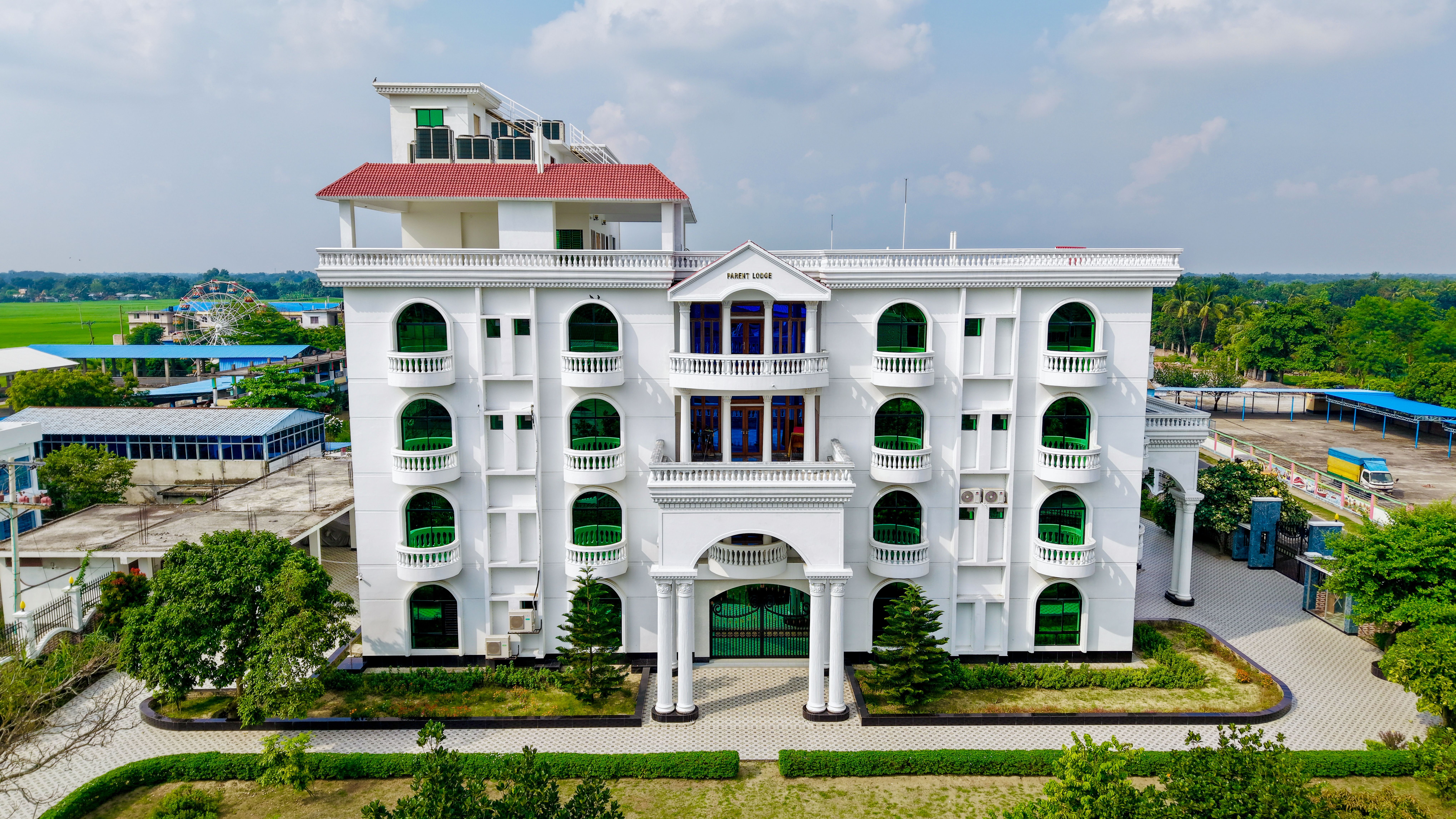 Architectural photo of a beautiful multi-storey white building with green accents and a red roof.