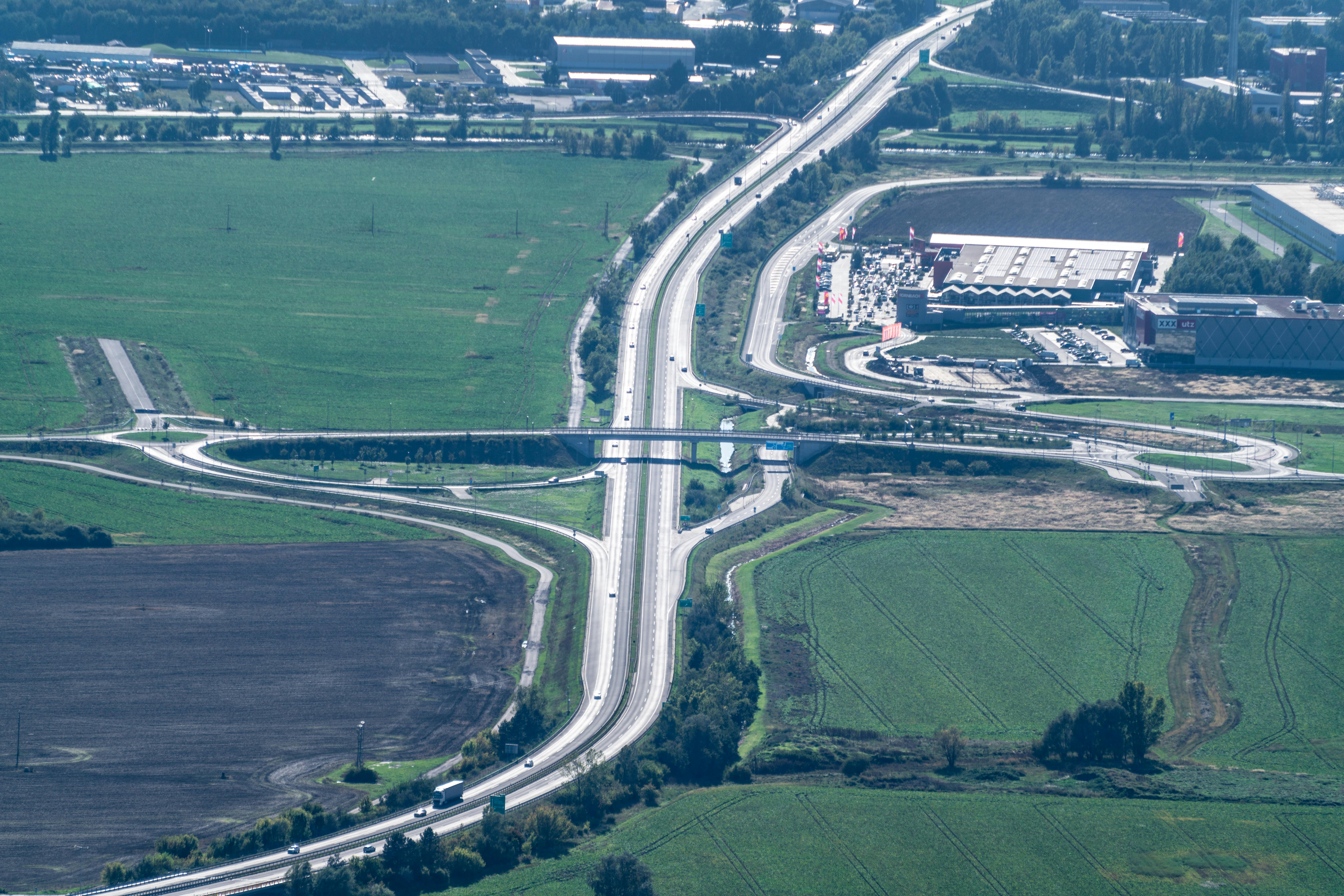 Aerial view of a busy highway and green fields near Nitra, Slovakia, on a sunny summer day.