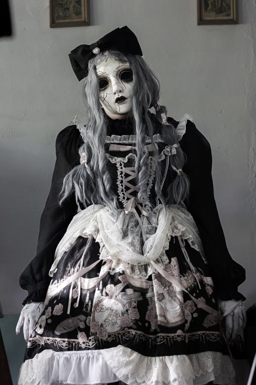 Free Eerie gothic lolita doll in lace dress and white mask indoors, spooky atmosphere. Stock Photo