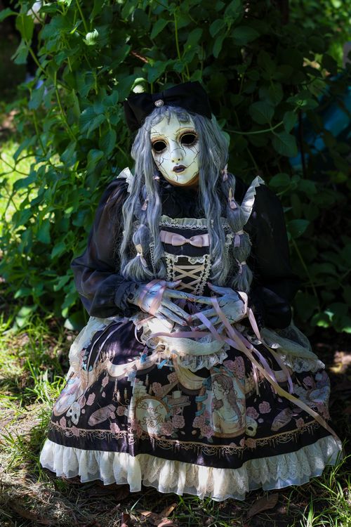 Free A doll with an intricately detailed Victorian-inspired Gothic outfit sitting outdoors, exuding mystery and elegance. Stock Photo