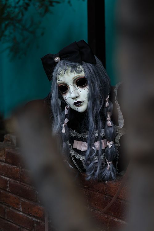 Free Creepy doll with a Gothic look leaning on a brick wall. Perfect for horror themes. Stock Photo