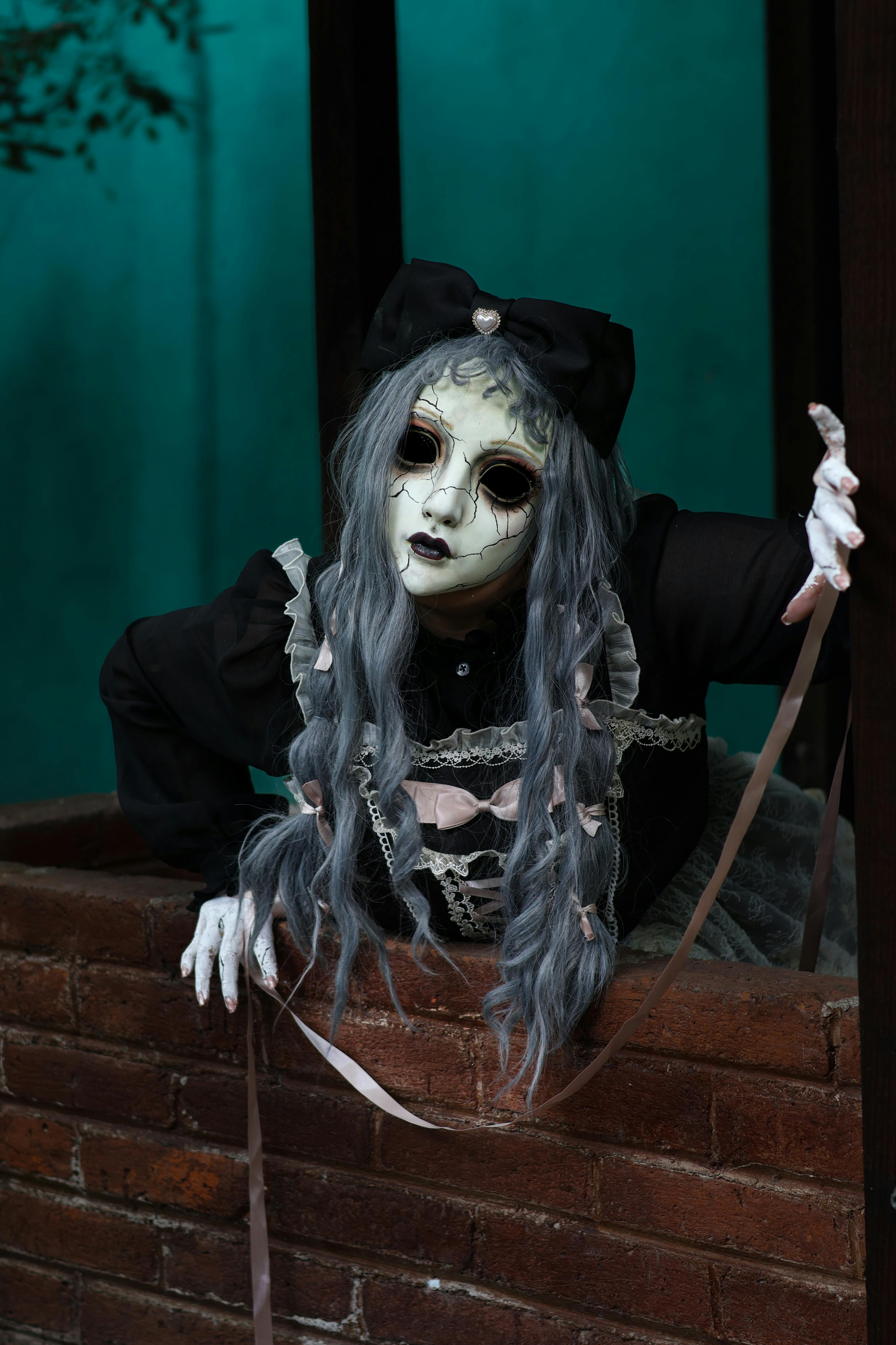 Miễn phí Búp bê kỳ lạ với trang phục gothic và mặt nạ xuất hiện từ giếng trong bối cảnh ánh sáng mờ ảo. Ảnh lưu trữ