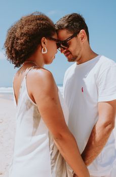 A couple shares a tender moment on a sunny beach in Rio de Janeiro, Brazil.
