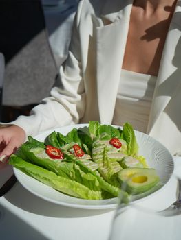 Fresh salad with avocado, lettuce, and cherry tomatoes served in a stylish setting.