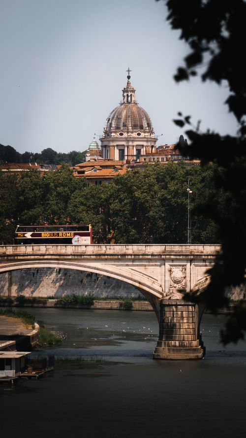 Free Iconic view of St. Peter's Basilica and a bridge over the Tiber River in Rome. Stock Photo