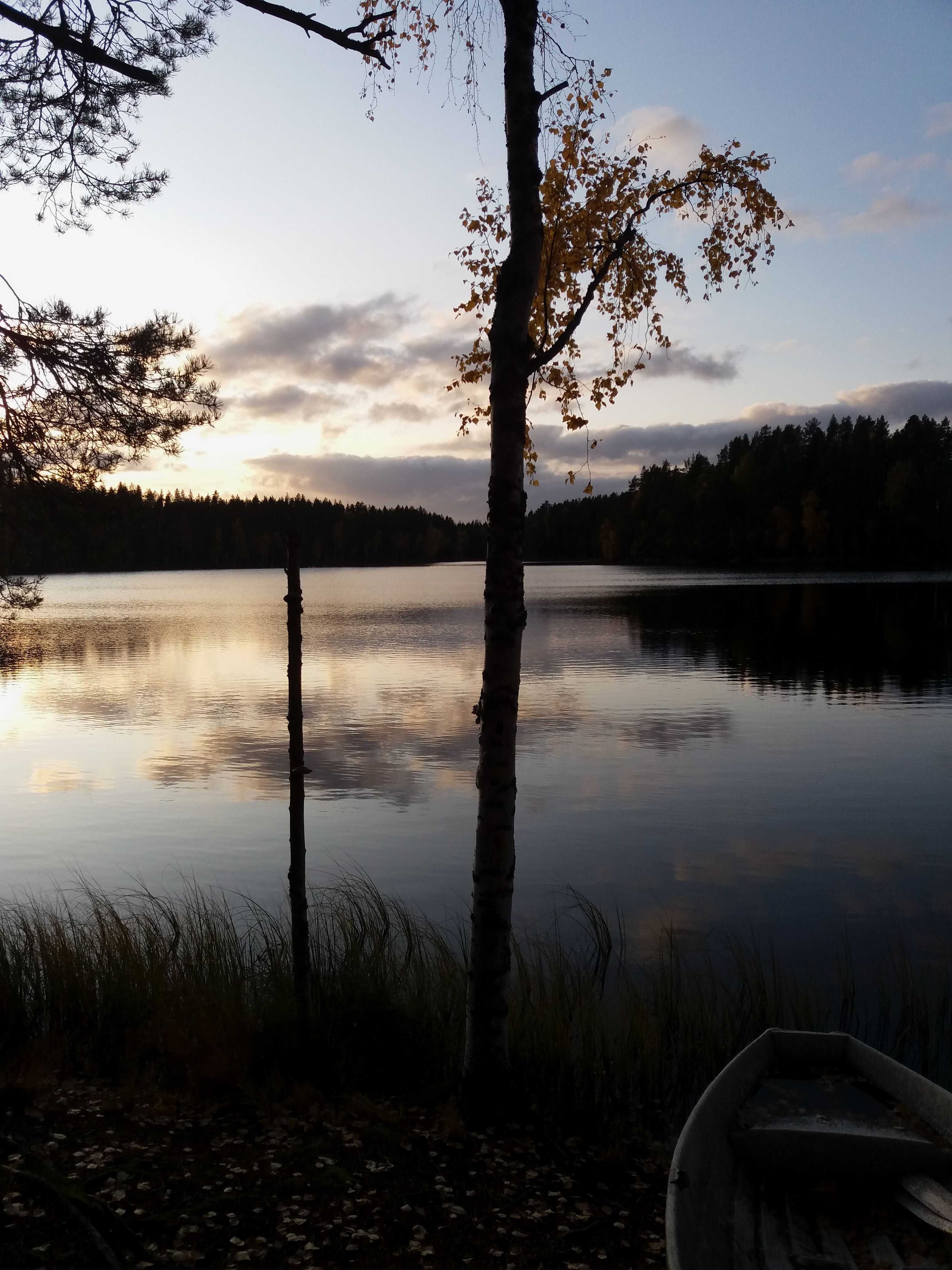 Tranquil lake scene at sunrise with autumn foliage reflecting on the water.