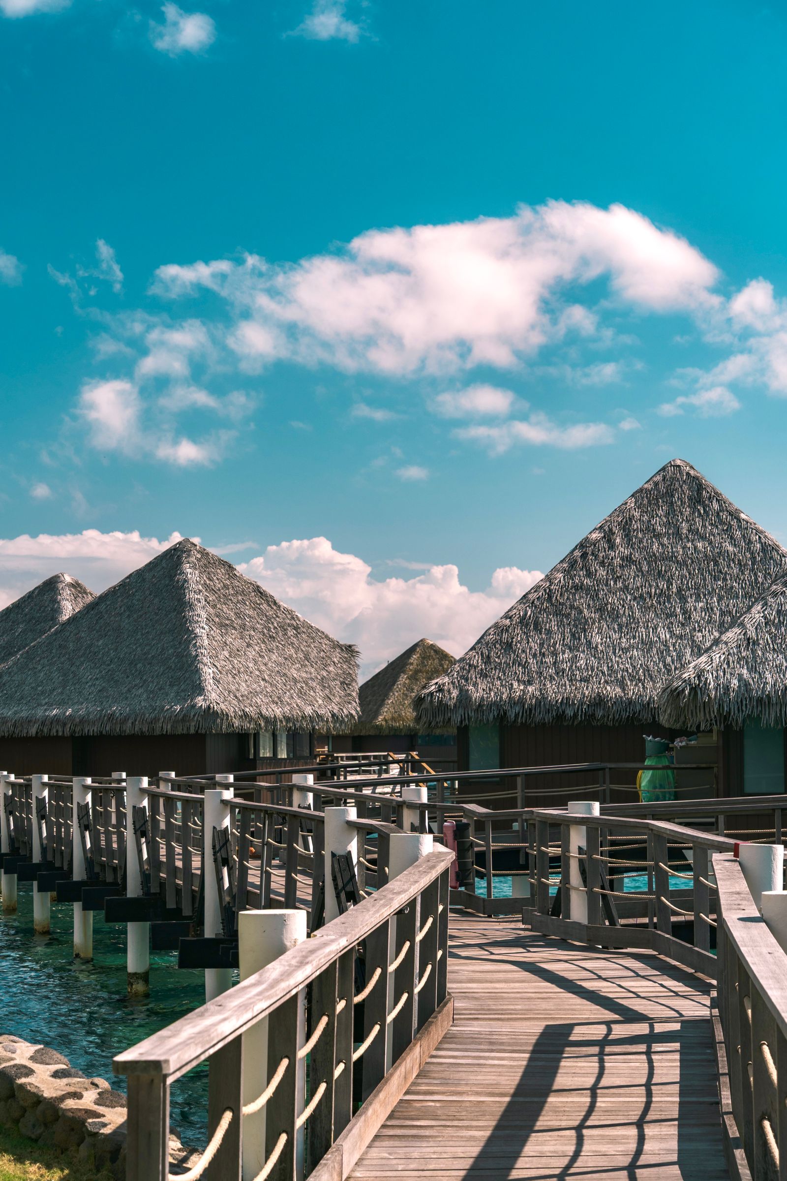 A wooden boardwalk leading to thatched overwater bungalows in the Windward Islands of French Polynesia