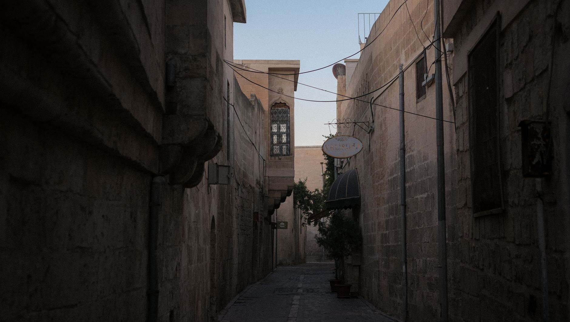 Narrow lane inside the Venetian walls of old Nicosia with sandstone houses and a mosque minaret behind