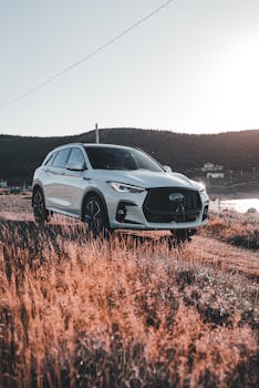A modern SUV parked on a rural road with mountains in the background, captured at sunrise.