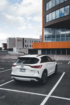 A sleek white SUV parked in an urban lot under a cloudy sky.