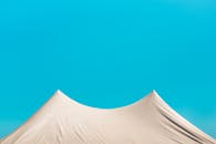 在鲜艳蓝天的映衬下，巴西极简主义帐篷的屋顶营造出一片宁静的夏日景象