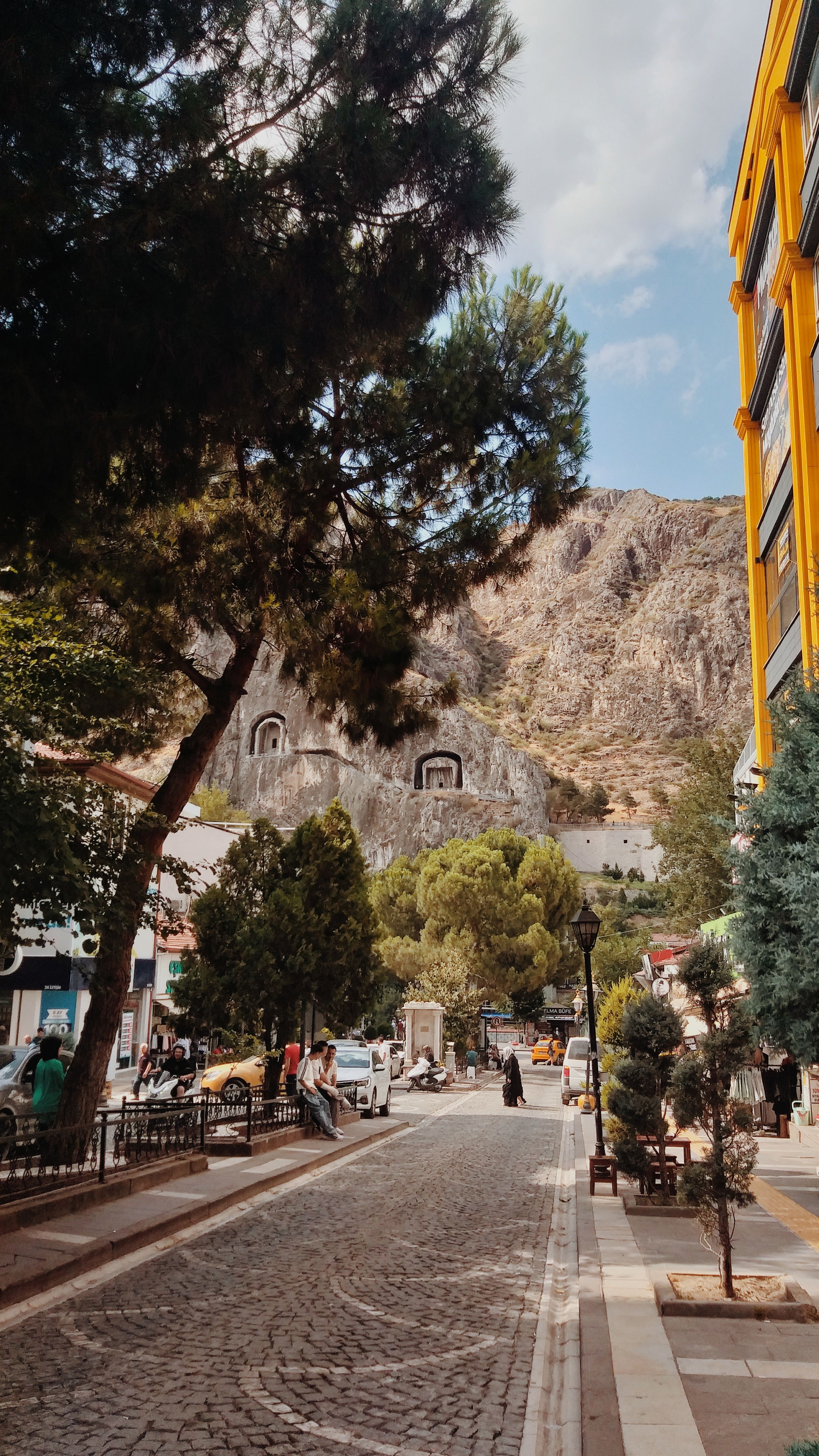 Quaint street scene in Amasya, Turkey with historical rock tombs and vibrant architecture.