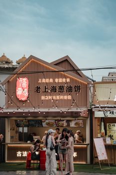 A vibrant outdoor market stall in Shanghai selling traditional snacks under string lights.
