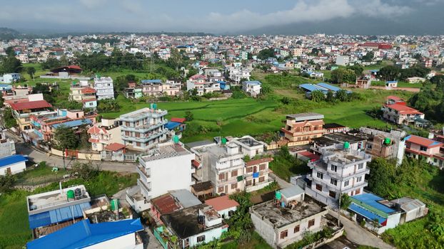 Aerial shot of a colorful urban neighborhood in Nepal, surrounded by greenery.