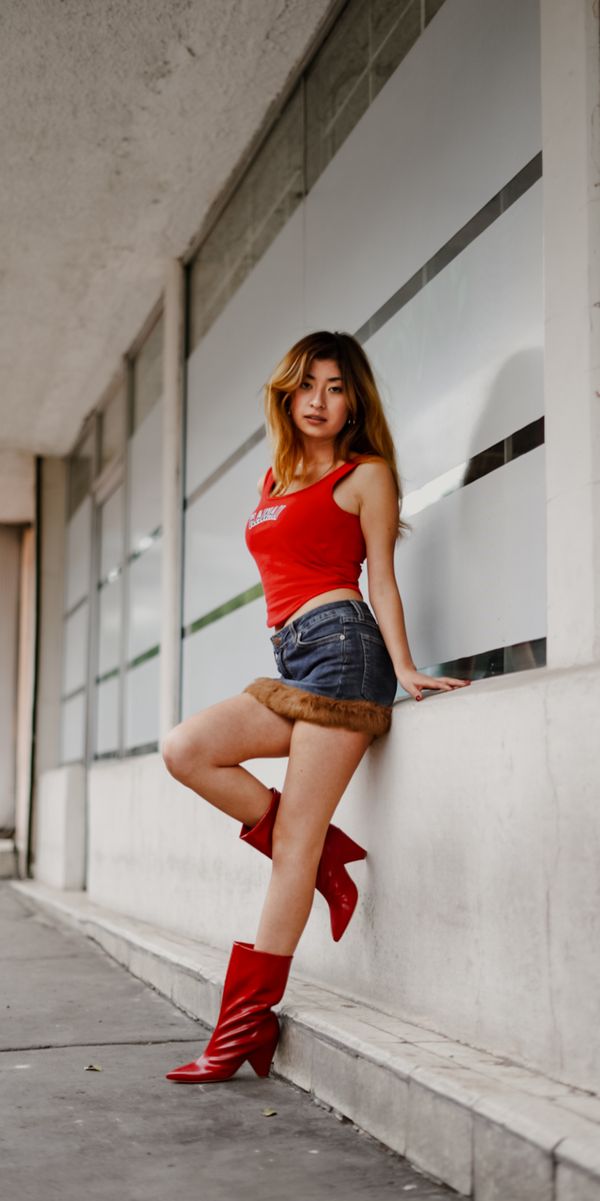 Woman in a cherry-red top with a dark denim mini skirt and boots