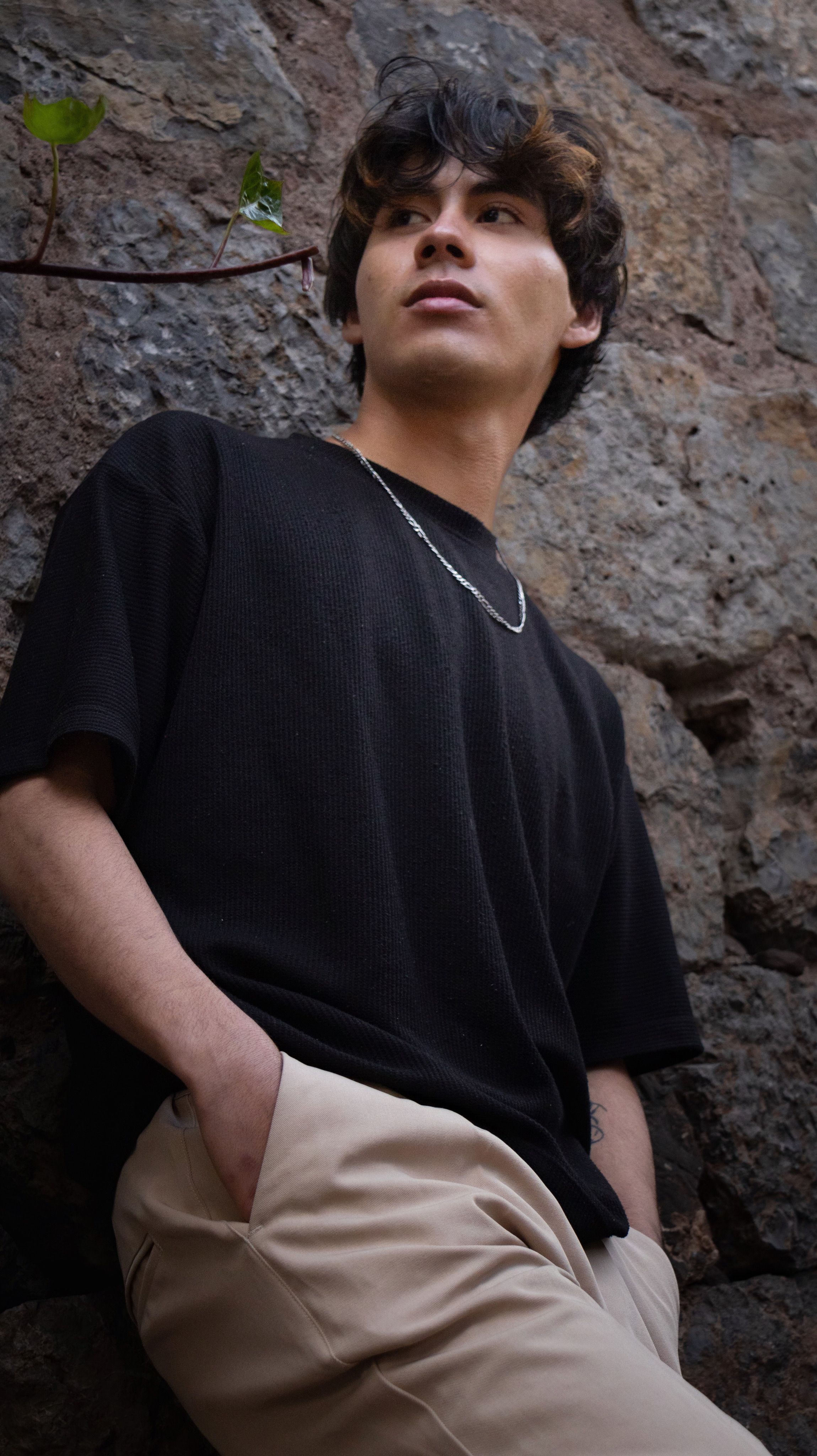 Young Man Leaning Against Stone Wall Outdoors · Free Stock Photo