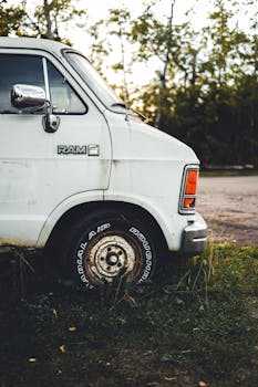 Old white van parked in a grassy rural area with trees in the background in Alberta, Canada.