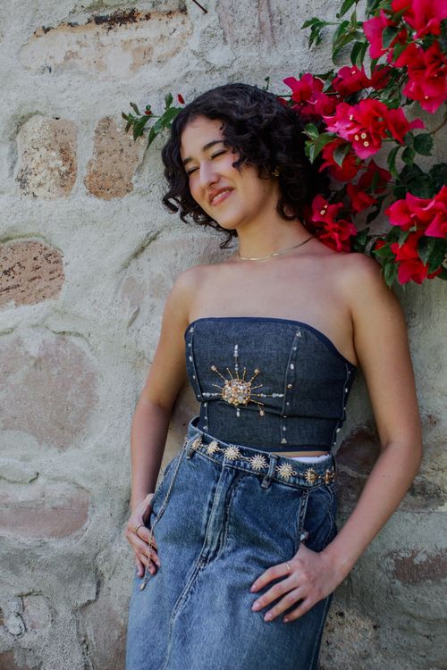 Free Elegant portrait of a woman in denim fashion against a stone wall and flowers. Stock Photo