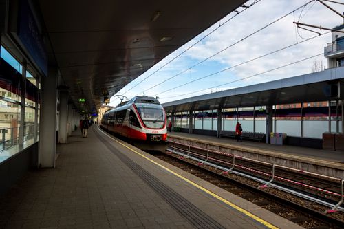 Free Red and white train arriving at a modern urban station platform on a clear day. Stock Photo