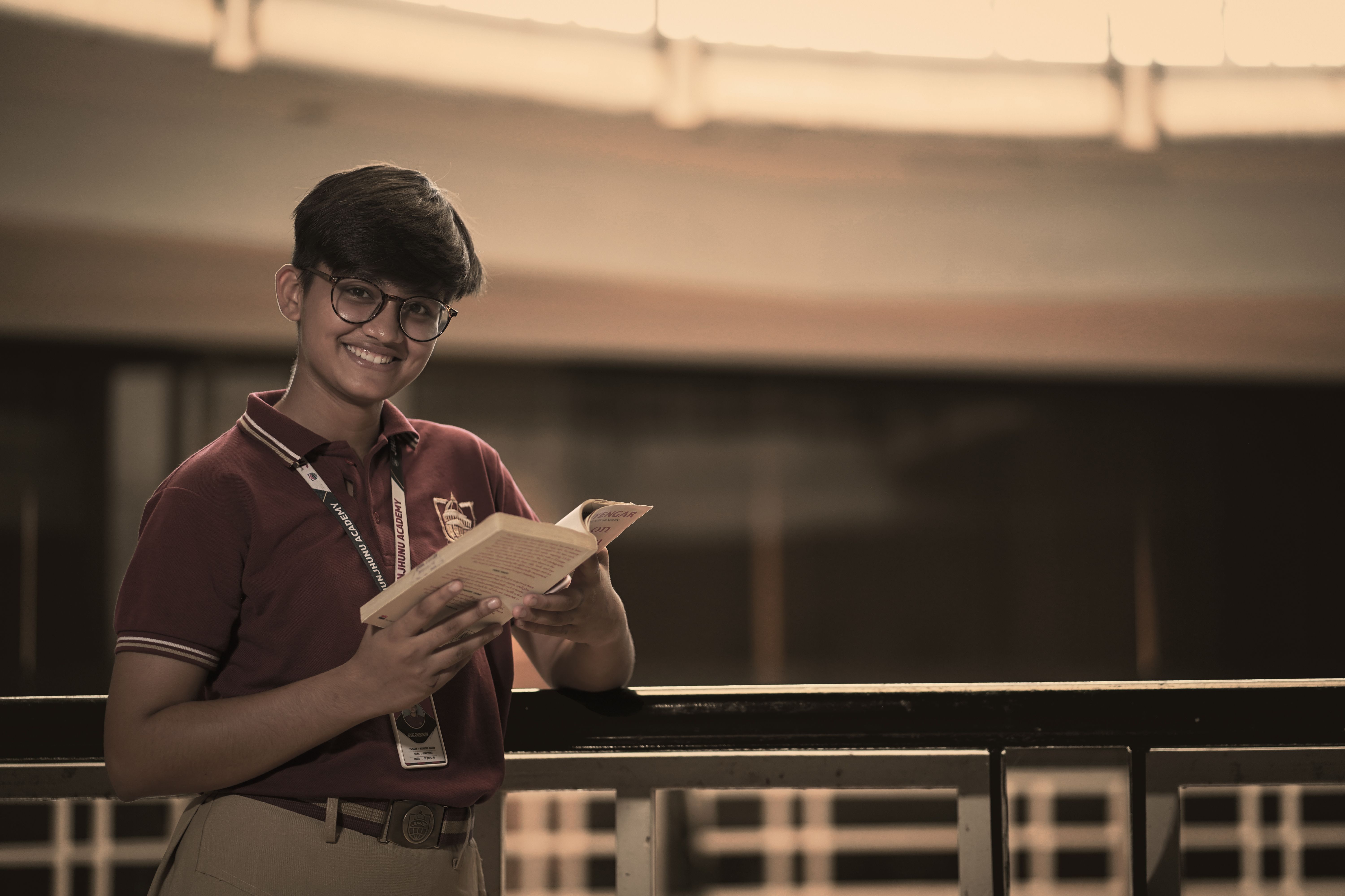 Smiling Student Holding a Book Indoors · Free Stock Photo